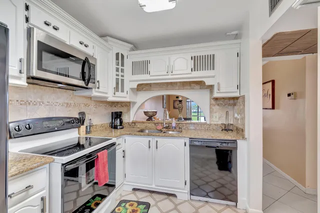 a kitchen with stainless steel appliances granite countertop a stove a sink and a microwave