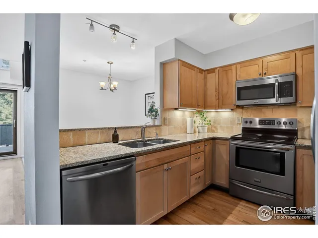 a kitchen with stainless steel appliances granite countertop a sink a stove a microwave and wooden floors