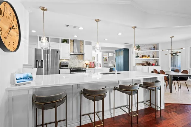 a kitchen with stainless steel appliances granite countertop a dining table chairs stove and cabinets