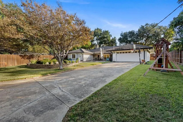 a view of a house with a big yard and large trees