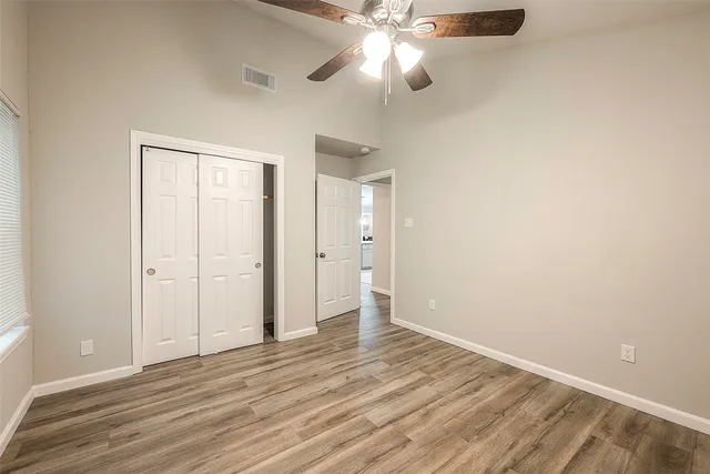 an empty room with a ceiling fan and wooden floor