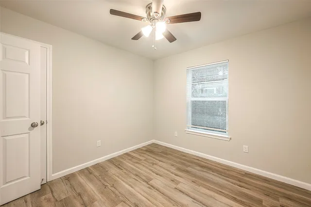 an empty room with windows and fan