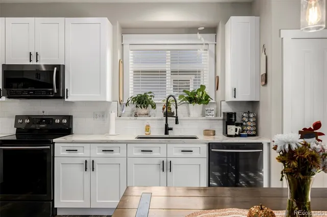 a kitchen with white cabinets and black appliances