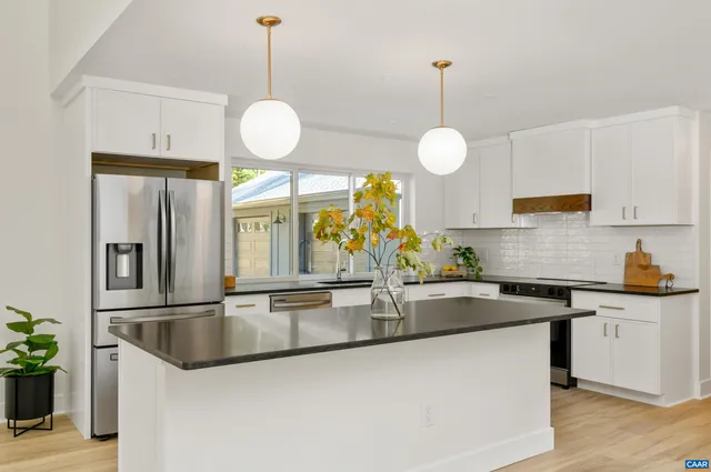 a kitchen with stainless steel appliances granite countertop a sink a stove and a wooden floors