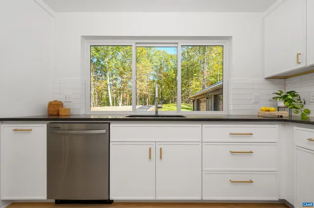 a kitchen with white cabinets and a window