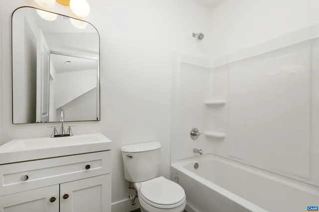 a bathroom with a bathtub shower sink vanity mirror and toilet