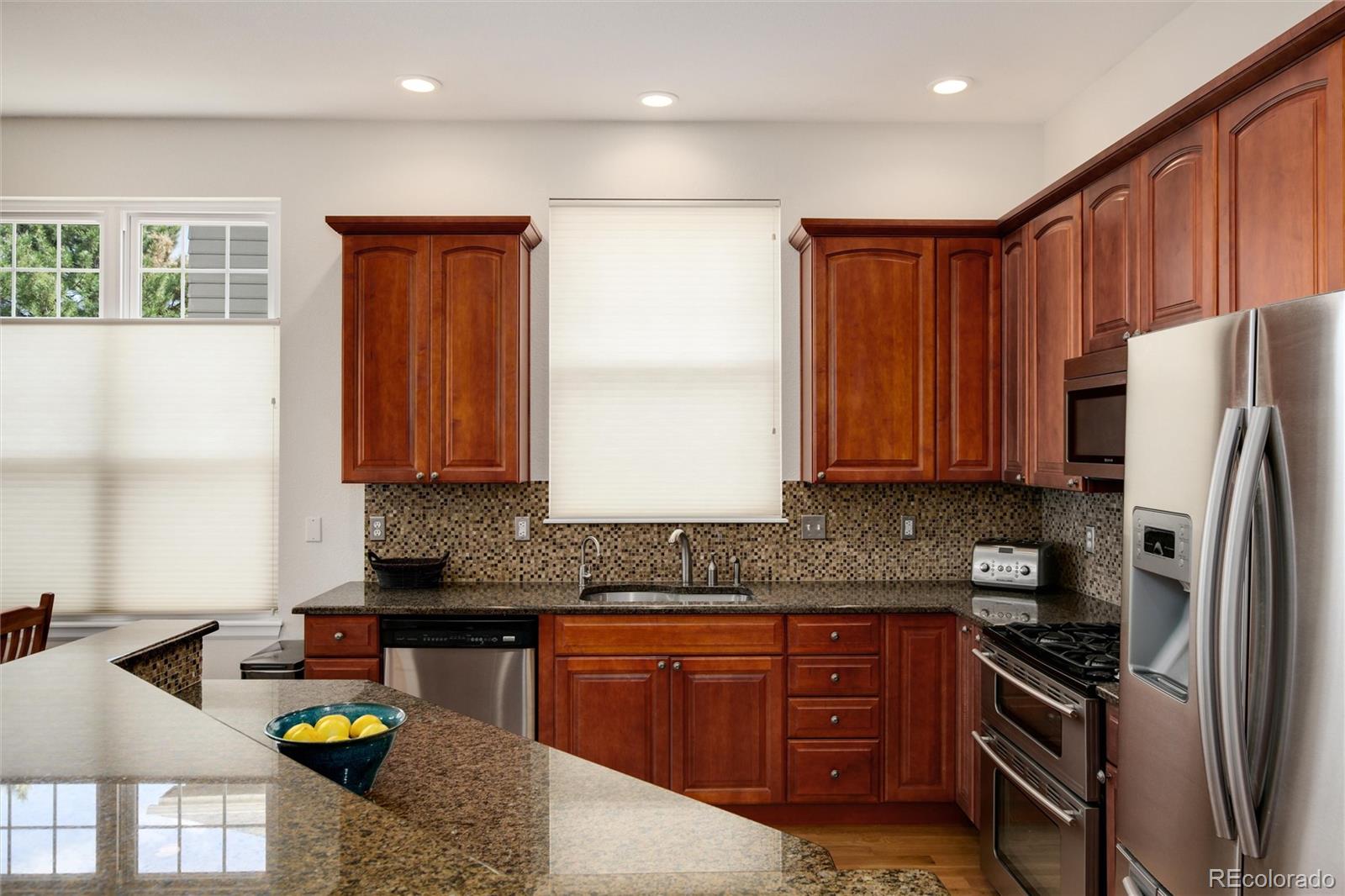3946 Mallard Street Highlands Ranch, CO 80126 - Photo 8 of 40 a kitchen with stainless steel appliances granite countertop a stove a sink and a refrigerator
