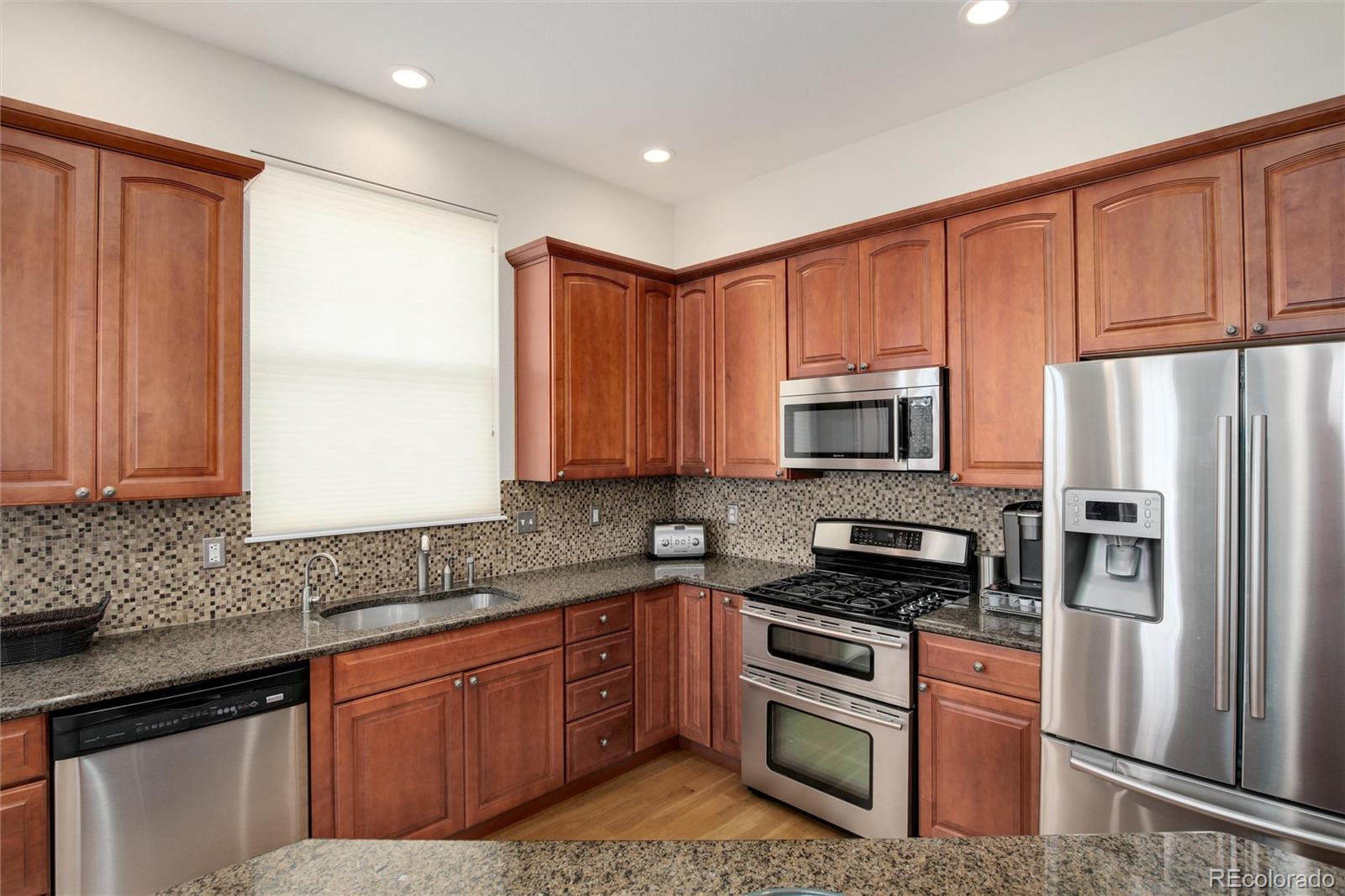 3946 Mallard Street Highlands Ranch, CO 80126 - Photo 9 of 40 a kitchen with stainless steel appliances granite countertop a refrigerator sink and cabinets