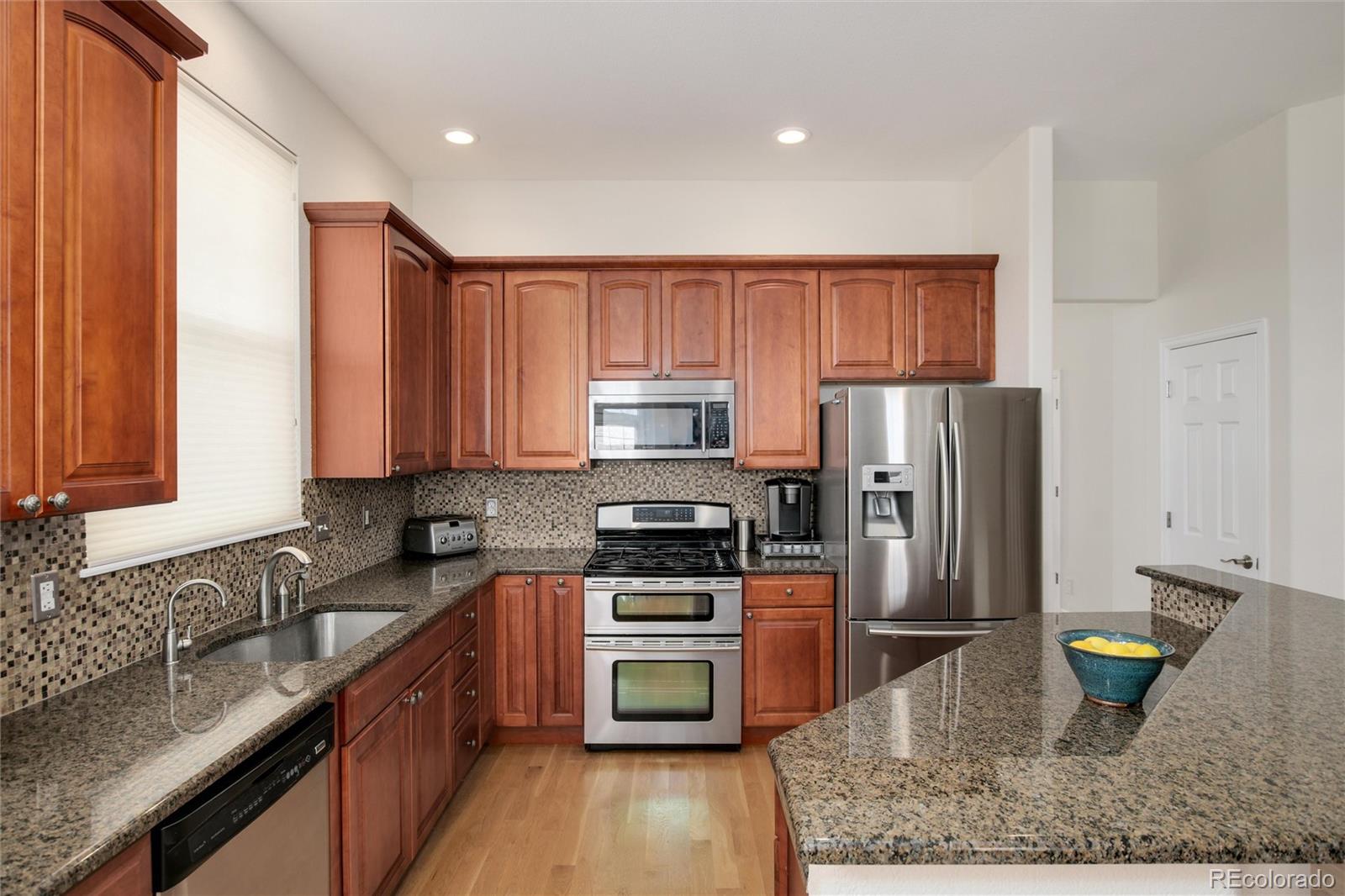3946 Mallard Street Highlands Ranch, CO 80126 - Photo 10 of 40 a kitchen with a refrigerator a sink and wooden cabinets