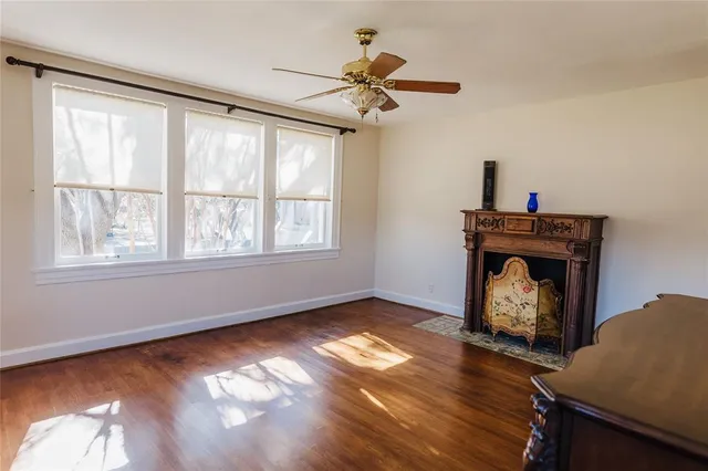 a view of an empty room with wooden floor fireplace and a window