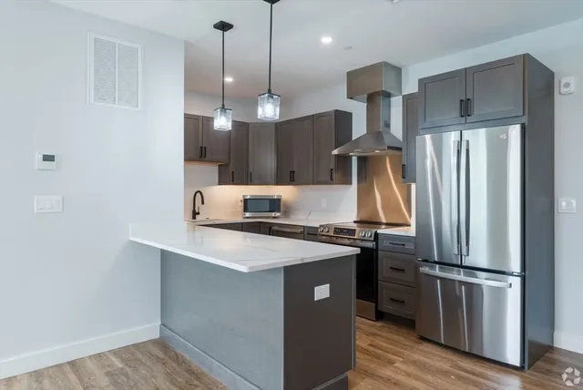 a kitchen with stainless steel appliances a sink a stove a refrigerator and island