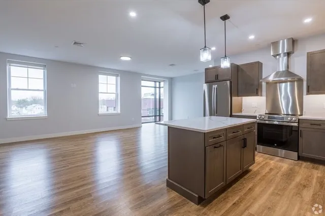 a kitchen with stainless steel appliances granite countertop a sink a stove a refrigerator and a wooden floor