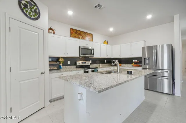 a kitchen with stainless steel appliances granite countertop a refrigerator a stove a sink and a refrigerator