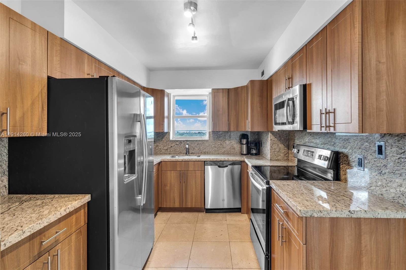 5101 Collins Avenue, Unit 12B Miami Beach, FL 33140 - Photo 6 of 13 a kitchen with stainless steel appliances granite countertop a refrigerator a stove top oven a sink and dishwasher