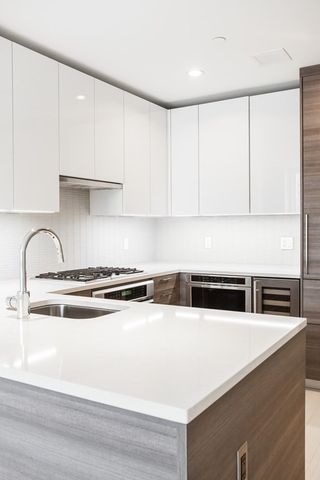 a kitchen with stainless steel appliances granite countertop a sink a stove and white cabinets with wooden floor