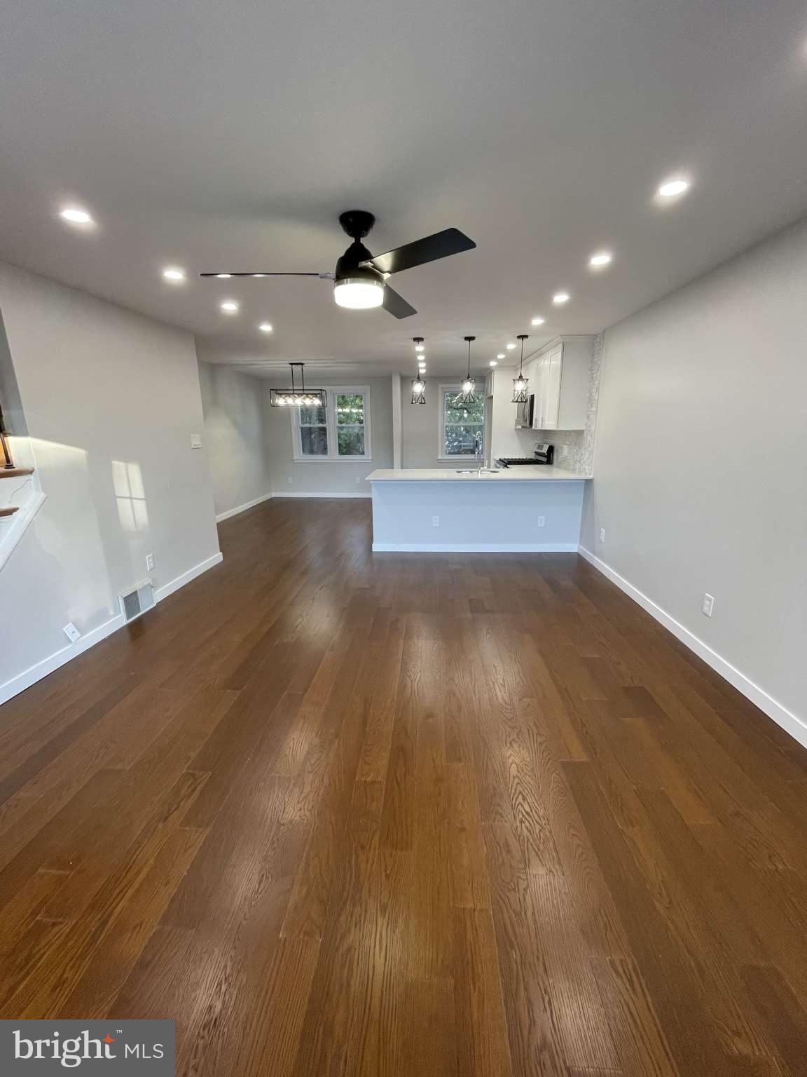 1305 Elson Road Brookhaven, PA 19015 - Photo 2 of 9 an empty room with wooden floor ceiling fan and kitchen view