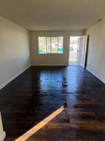 a view of empty room with window and wooden floor