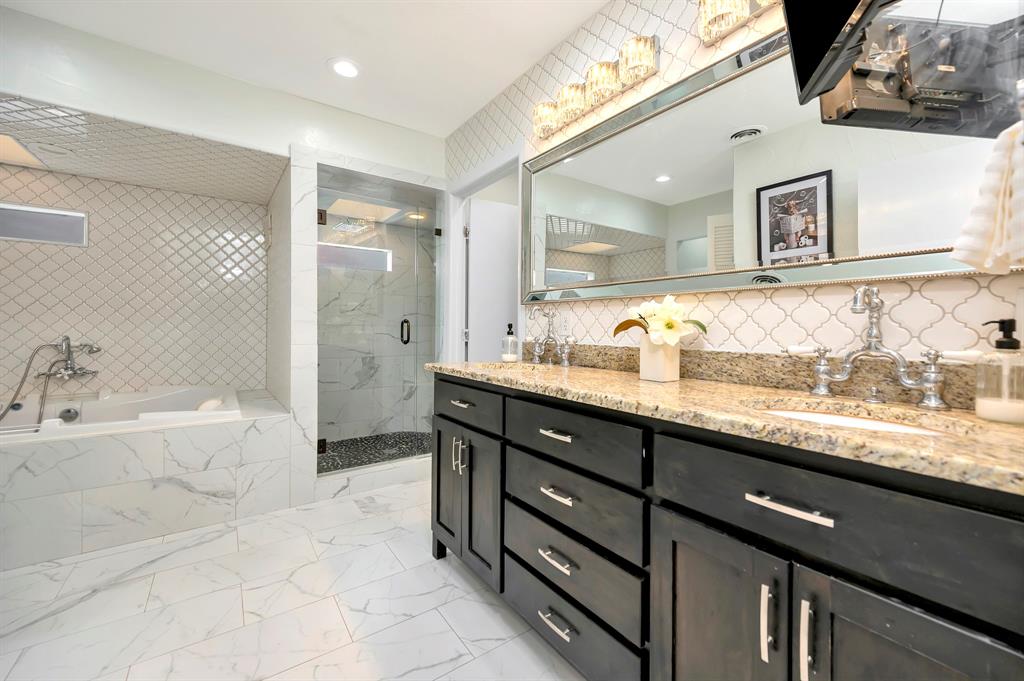 3413 Westcliff Road South Fort Worth, TX 76109 - Photo 16 of 26 a bathroom with a granite countertop sink a large mirror a bathtub and shower
