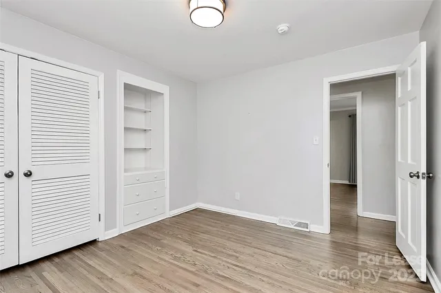 an empty room with wooden floor & closet area
