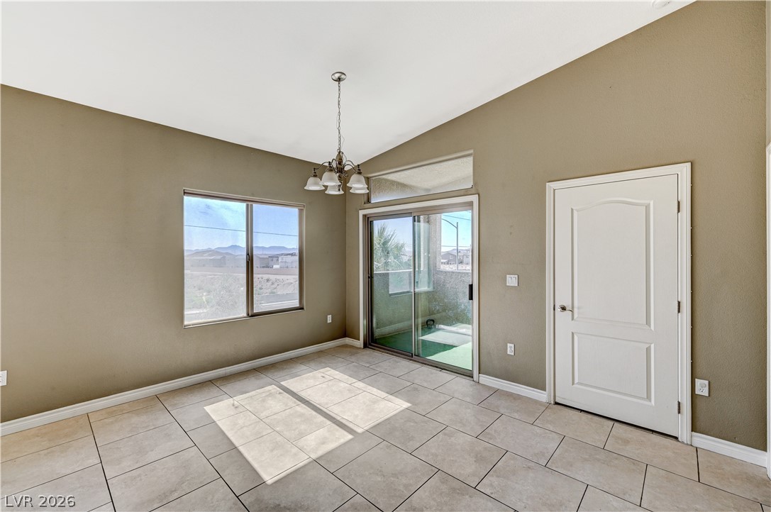 8985 South Durango Drive, Unit 2187 Las Vegas, NV 89113 - Photo 25 of 73 A well-lit room features a vaulted ceiling and direct access to outdoor space, ideal for dining or a flexible living area.