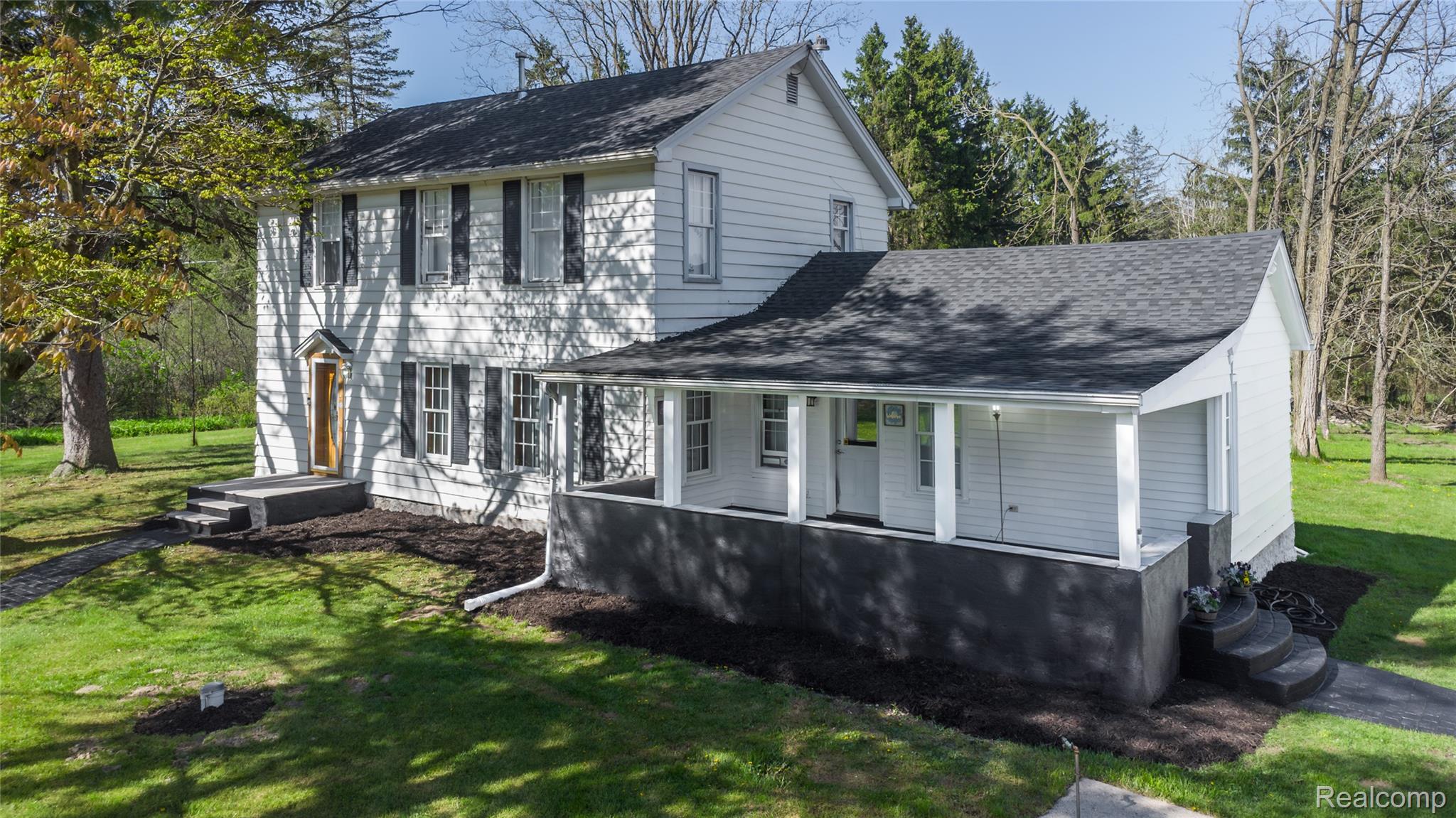 View of front of house featuring a front lawn and roof with shingles