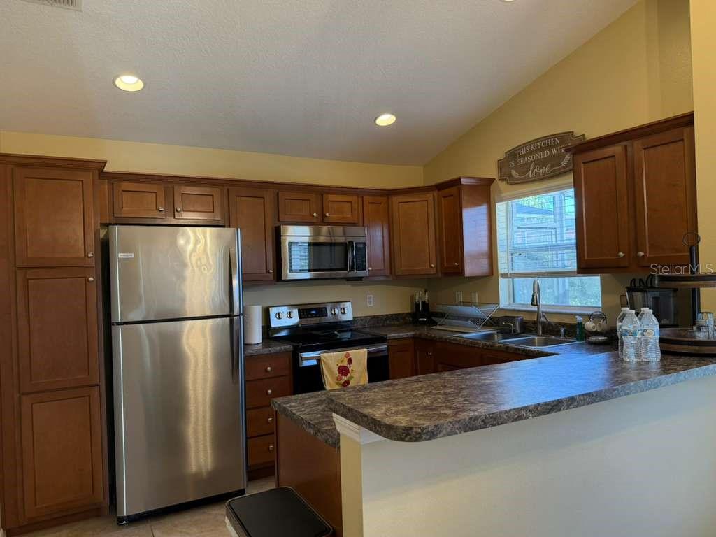 328 Robin Road Davenport, FL 33896 - Photo 12 of 17 a kitchen with stainless steel appliances granite countertop a refrigerator stove a sink dishwasher and microwave