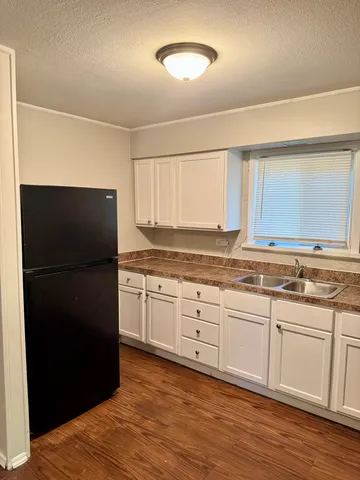 a kitchen with granite countertop white cabinets and refrigerator