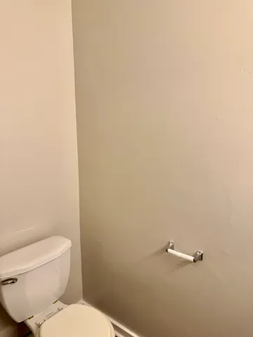 a white toilet sitting next to a white wall