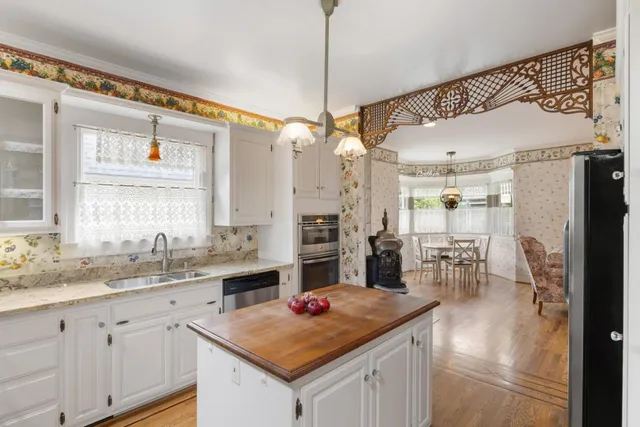 a kitchen with a stove a sink a refrigerator and dining table with wooden floor