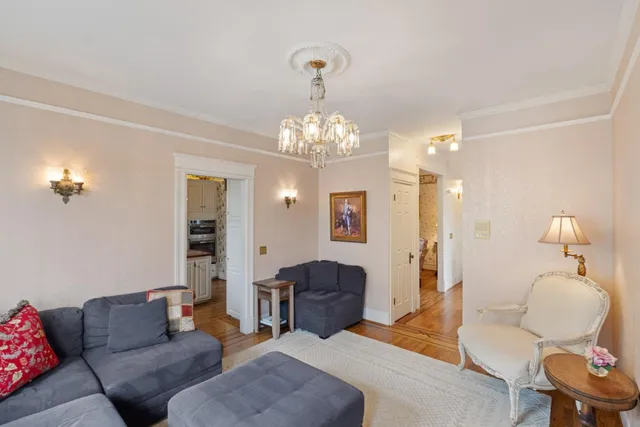 a living room with furniture a chandelier and a mirror