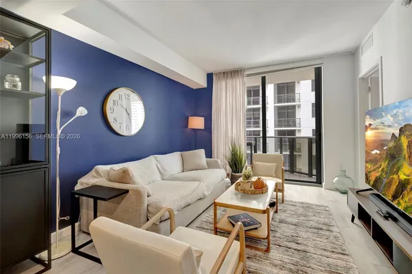 a living room with furniture a clock and a flat screen tv