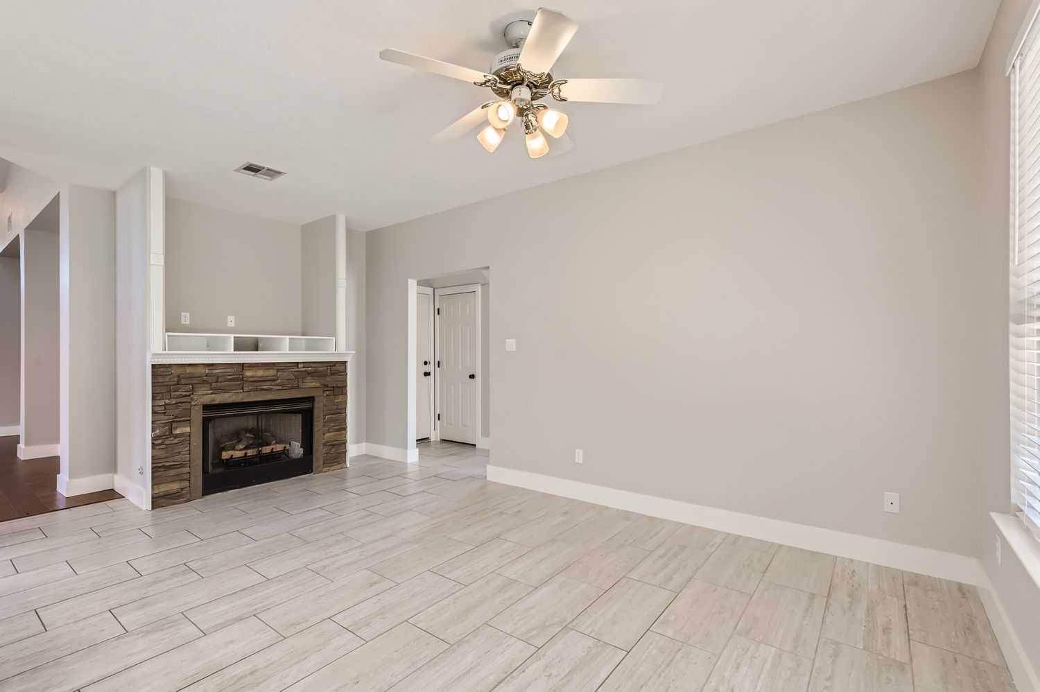 3805 Mankins Way Austin, TX 78728 - Photo 2 of 11 Unfurnished living room featuring a stone fireplace, ceiling fan, and wood tiled floors