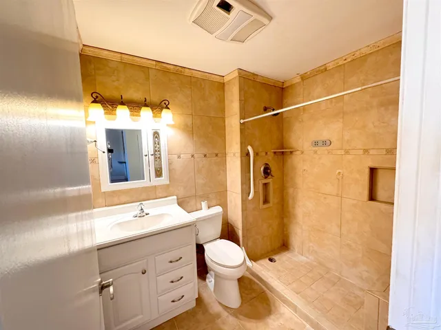 an empty room with chandelier fan and windows