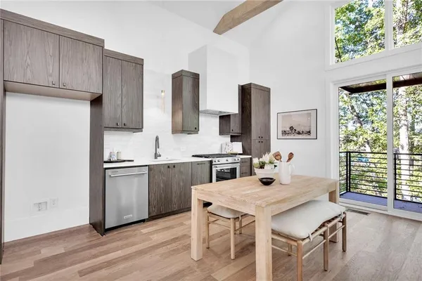 a kitchen with stainless steel appliances granite countertop a stove a sink dishwasher and a refrigerator with wooden floor