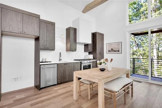 a kitchen with stainless steel appliances granite countertop a stove a sink dishwasher and a refrigerator with wooden floor