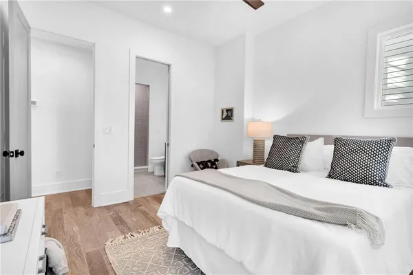 a bed sitting in a bedroom next to a window with a lamp on table and a large window