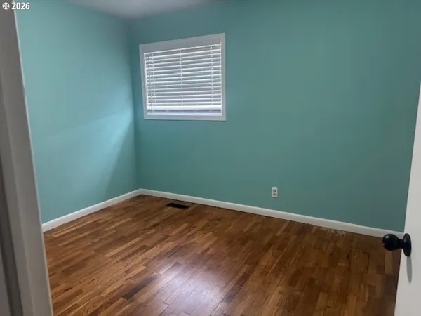 a view of an empty room with wooden floor and closet