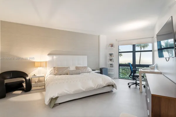 a bedroom with a bed a large window with table and chairs
