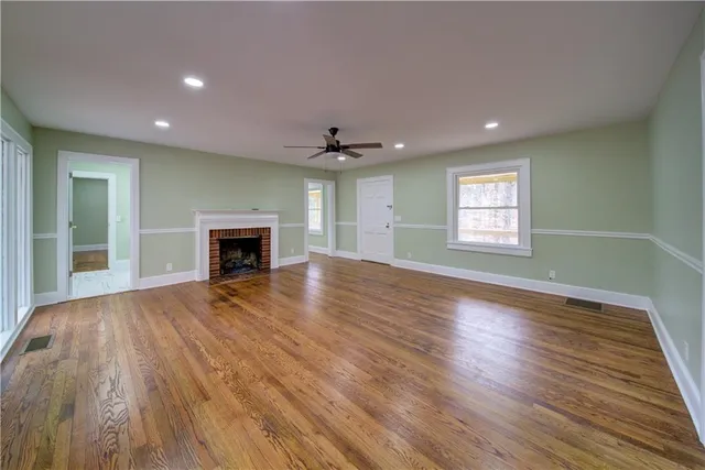 an empty room with wooden floor fireplace and a window