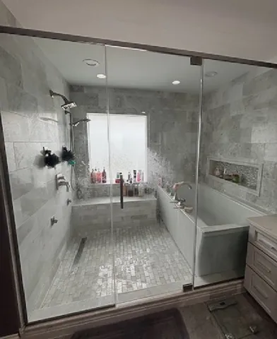 a bathroom with a tub a mirror and shower