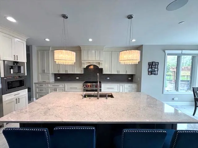 a kitchen with kitchen island granite countertop a sink a counter top space appliances and a window