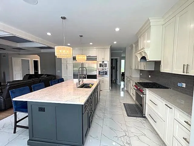 a large kitchen with stainless steel appliances kitchen island granite countertop a large stove a sink dishwasher and white cabinets with wooden floor