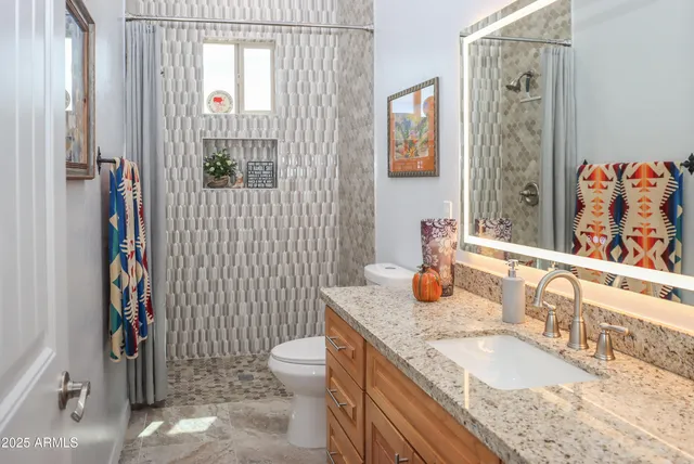 a bathroom with a granite countertop toilet sink and mirror