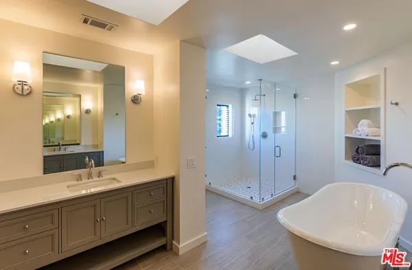 a spacious bathroom with a double vanity sink a large mirror and shower