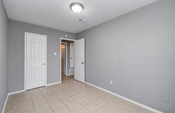 an empty room with wooden floor ceiling fan and windows