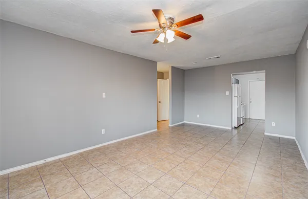 an empty room with chandelier fan and windows