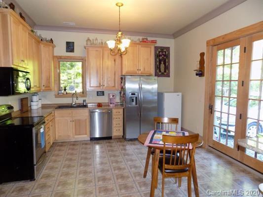 1117 Ponder Road Mill Spring, NC 28756 - Photo 5 of 39 a kitchen with stainless steel appliances granite countertop a stove top oven a refrigerator a sink dishwasher a dining table and chairs with wooden floor