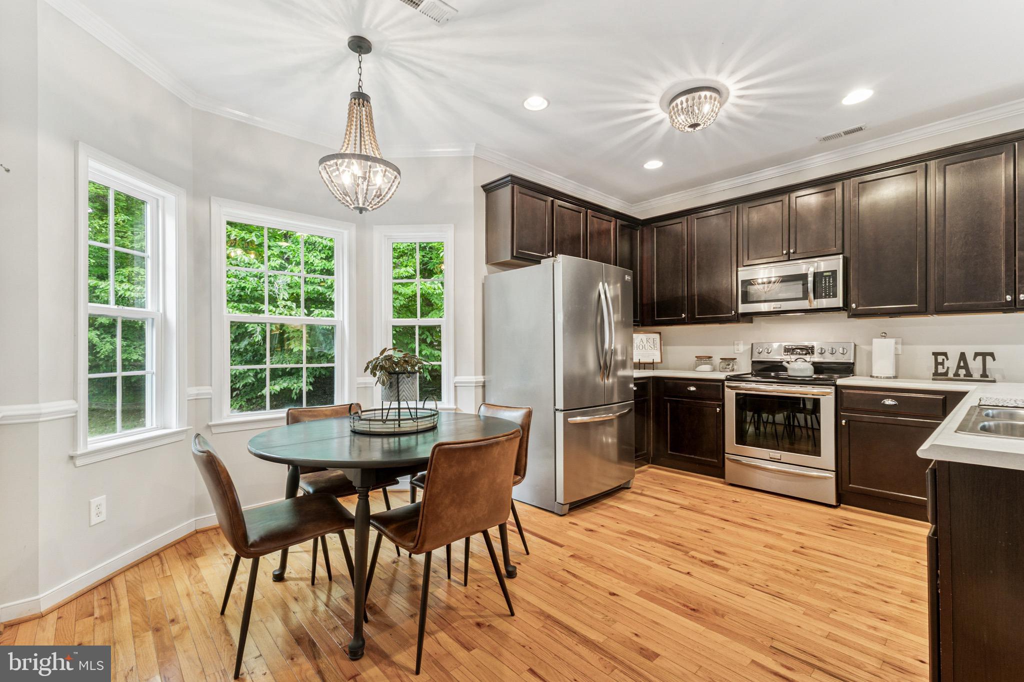 6108 Bills Road Mineral, VA 23117 - Photo 14 of 43 a kitchen with stainless steel appliances granite countertop a stove top oven a refrigerator a kitchen island a sink dishwasher a dining table and chairs with wooden floor