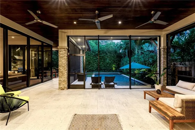 a view of pool with lawn chairs and floor to ceiling window