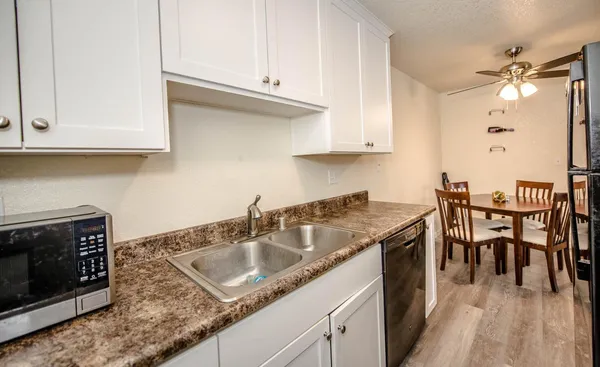 a kitchen with granite countertop a sink a stove and cabinets